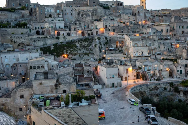 Matera; İtalya - 15 Eylül 2019: Matera şehrinin akşam manzarası; Matera şehrinin tarihi bir bölgesi olan Sassi di Matera 'daki eski binaların renkli ışıklarıyla. Basilicata. İtalya