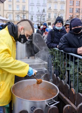 Krakow, Polonya - 19 Aralık 2021: Krakow 'daki ana meydandaki fakir ve evsizler için Noel arifesi. Covid salgınına rağmen Kosciuszko grubu Krakow 'daki açık havada en büyük arifeyi hazırlıyor.