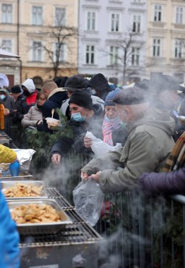 Krakow, Polonya - 19 Aralık 2021: Krakow 'daki ana meydandaki fakir ve evsizler için Noel arifesi. Covid salgınına rağmen Kosciuszko grubu Krakow 'daki açık havada en büyük arifeyi hazırlıyor.