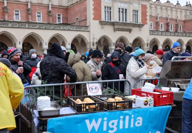 Krakow, Polonya - 19 Aralık 2021: Krakow 'daki ana meydandaki fakir ve evsizler için Noel arifesi. Covid salgınına rağmen Kosciuszko grubu Krakow 'daki açık havada en büyük arifeyi hazırlıyor.