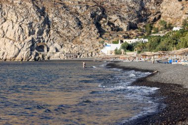 Kamari, Santorini, Yunanistan - 3 Temmuz 2021: Santorini 'deki siyah volkanik Kamari plajında güneşlik. Cyclades, Yunanistan