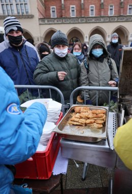 Krakow, Polonya - 19 Aralık 2021: Krakow 'daki ana meydandaki fakir ve evsizler için Noel arifesi. Covid salgınına rağmen Kosciuszko grubu Krakow 'daki açık havada en büyük arifeyi hazırlıyor.
