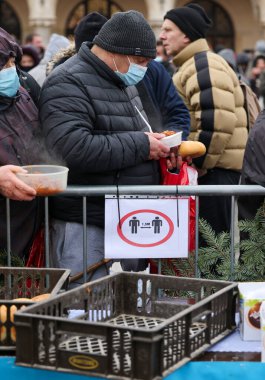 Krakow, Polonya - 19 Aralık 2021: Krakow 'daki ana meydandaki fakir ve evsizler için Noel arifesi. Covid salgınına rağmen Kosciuszko grubu Krakow 'daki açık havada en büyük arifeyi hazırlıyor.