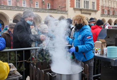Krakow, Polonya - 19 Aralık 2021: Krakow 'daki ana meydandaki fakir ve evsizler için Noel arifesi. Covid salgınına rağmen Kosciuszko grubu Krakow 'daki açık havada en büyük arifeyi hazırlıyor.