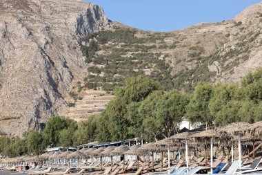 Kamari, Santorini, Yunanistan - 3 Temmuz 2021: Santorini 'deki siyah volkanik Kamari plajında güneşlik. Cyclades, Yunanistan
