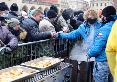 Krakow, Polonya - 19 Aralık 2021: Krakow 'daki ana meydandaki fakir ve evsizler için Noel arifesi. Covid salgınına rağmen Kosciuszko grubu Krakow 'daki açık havada en büyük arifeyi hazırlıyor.