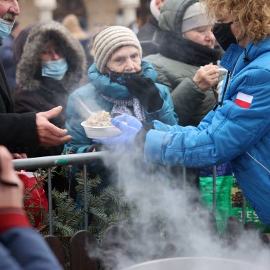 Krakow, Polonya - 19 Aralık 2021: Krakow 'daki ana meydandaki fakir ve evsizler için Noel arifesi. Covid salgınına rağmen Kosciuszko grubu Krakow 'daki açık havada en büyük arifeyi hazırlıyor.