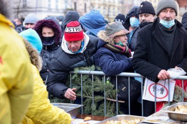 Krakow, Polonya - 19 Aralık 2021: Krakow 'daki ana meydandaki fakir ve evsizler için Noel arifesi. Covid salgınına rağmen Kosciuszko grubu Krakow 'daki açık havada en büyük arifeyi hazırlıyor.