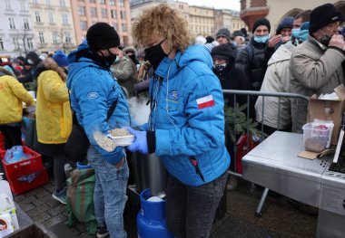 Krakow, Polonya - 19 Aralık 2021: Krakow 'daki ana meydandaki fakir ve evsizler için Noel arifesi. Covid salgınına rağmen Kosciuszko grubu Krakow 'daki açık havada en büyük arifeyi hazırlıyor.