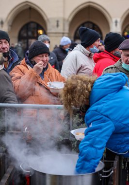 Krakow, Polonya - 19 Aralık 2021: Krakow 'daki ana meydandaki fakir ve evsizler için Noel arifesi. Covid salgınına rağmen Kosciuszko grubu Krakow 'daki açık havada en büyük arifeyi hazırlıyor.