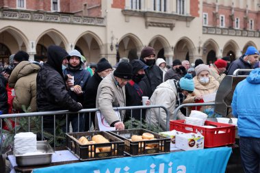 Krakow, Polonya - 19 Aralık 2021: Krakow 'daki ana meydandaki fakir ve evsizler için Noel arifesi. Covid salgınına rağmen Kosciuszko grubu Krakow 'daki açık havada en büyük arifeyi hazırlıyor.