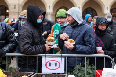 Krakow, Polonya - 19 Aralık 2021: Krakow 'daki ana meydandaki fakir ve evsizler için Noel arifesi. Covid salgınına rağmen Kosciuszko grubu Krakow 'daki açık havada en büyük arifeyi hazırlıyor.