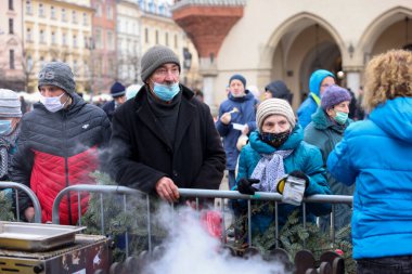 Krakow, Polonya - 19 Aralık 2021: Krakow 'daki ana meydandaki fakir ve evsizler için Noel arifesi. Covid salgınına rağmen Kosciuszko grubu Krakow 'daki açık havada en büyük arifeyi hazırlıyor.