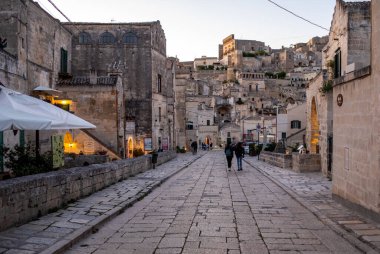 Matera, İtalya - 20 Eylül 2019: Matera, İtalya 'nın akşam manzarası, Sassi di Matera şehrinin tarihi bir bölgesi olan Sassi di Matera' daki kaldırım kafelerinin avlularını aydınlatan renkli ışıklarla. Basilicata. İtalya