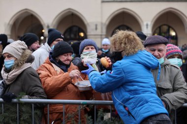 Krakow, Polonya - 19 Aralık 2021: Krakow 'daki ana meydandaki fakir ve evsizler için Noel arifesi. Covid salgınına rağmen Kosciuszko grubu Krakow 'daki açık havada en büyük arifeyi hazırlıyor.