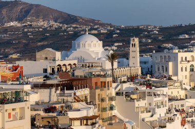 Fira, Santorini, Yunanistan - 27 Haziran 2021: Yunanistan 'ın Kiklad adasındaki Santorini Adası' nda gün batımının ılık ışınlarında beyazlatılmış Fira kasabası