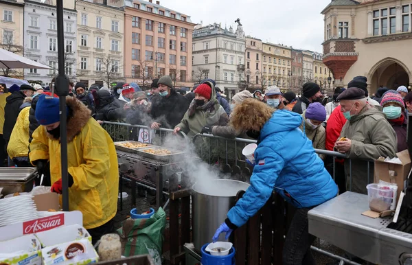 Krakow, Polonya - 19 Aralık 2021: Krakow 'daki ana meydandaki fakir ve evsizler için Noel arifesi. Covid salgınına rağmen Kosciuszko grubu Krakow 'daki açık havada en büyük arifeyi hazırlıyor.