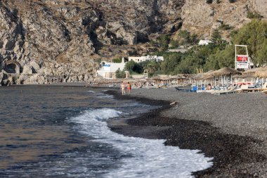 Kamari, Santorini, Yunanistan - 3 Temmuz 2021: Santorini 'deki siyah volkanik Kamari plajında güneşlik. Cyclades, Yunanistan