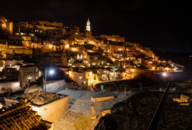 Matera 'daki antik Sassi bölgesinde geceleri, antik mağara evleri ile tanınan şaşırtıcı aydınlık binalar. Basilicata. İtalya