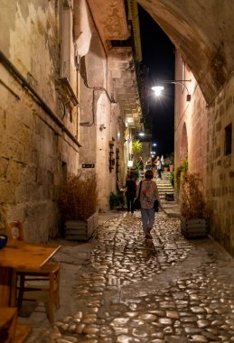Matera, İtalya - 17 Eylül 2019: Matera şehrinin tarihi bir bölgesi olan Sassi di Matera 'daki Cobblestone caddesinde yürüyüş yapan turistler. Basilicata. İtalya