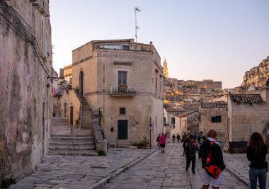 Matera, İtalya - 20 Eylül 2019: Matera şehrinin tarihi bir bölgesi olan Sassi di Matera 'daki Cobblestone caddesinde yürüyüş yapan turistler. Basilicata. İtalya