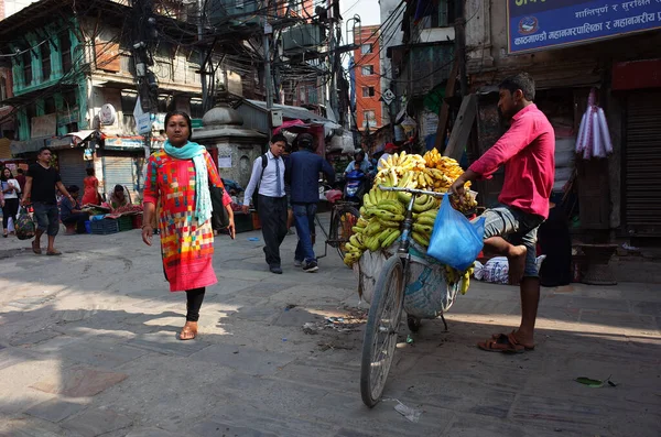 ネパール カトマンズ 2019年6月17日 自転車の果物販売業者がカトマンズ通りでバナナを販売しています ネパール人女性が赤い伝統的な服を着て歩く — ストック写真