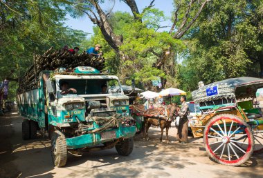 Inwa (Ava), Myanmar - 10 Ocak 2019: Camsız çıngıraklı yılan kamyonu yol boyunca at arabaları arasında bambu çubuklarla dolu