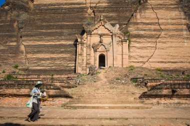 Mingun, Myanmar - 13 Ocak 2020: Mingun Pahtodawyi pagoda 'nın önünde yürüyen kadın sokak satıcısı - deprem tarafından yıkılan dev antik bir stupa