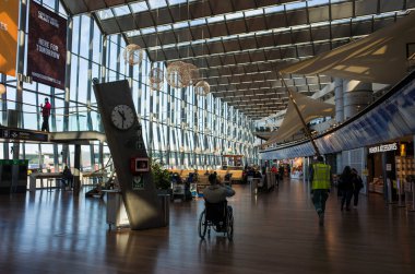 Stockholm, İsveç - 25 Mart 2021: Arlanda Havalimanı 'nın içi, tekerlekli sandalyedeki engelli saat ile büyük, parlak salonda 