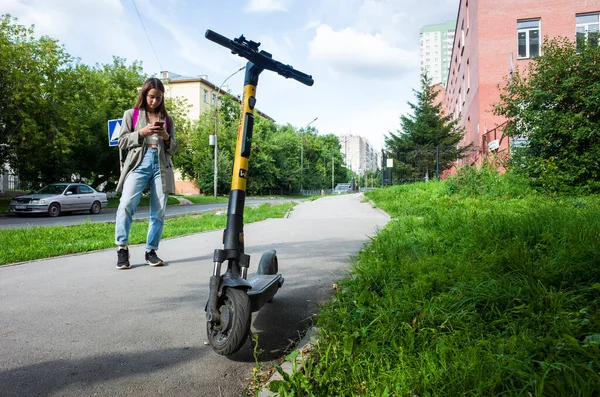 Novosibirsk ロシア 2021 夏にシベリアの電動スクーター 電気都市交通のロックを解除するために携帯電話を使用して若い女性 — ストック写真