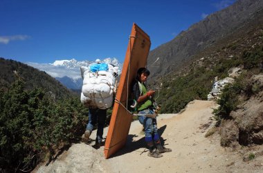 Sagarmatha Ulusal Parkı, Nepal - 17 Mayıs 2019: Porter Himalayalar 'da süper ağır bir yük altında dinleniyor. Everest yolu Pangboche yakınlarında, Sagarmatha Ulusal Parkı, Solukhumbu, Nepal