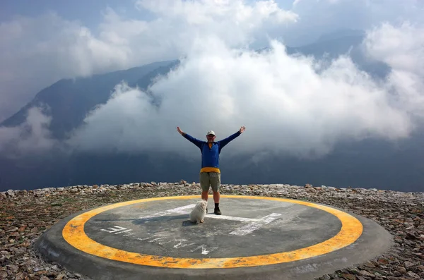 Turista Feliz Com Braços Levantados Cão Fofo Branco Heliporto Montanhas — Fotografia de Stock