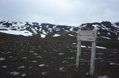 Villarrica Ulusal Pucon, Şili - 19 Aralık 2018: Quetrupillan volkan ahşap tabela tahtası - Villarrica Traverse yürüyüş yolu, volkanik arazi seyrek bitki örtüsü, bulutsuz hava bulutları