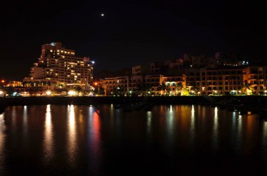 Dibba Al-Fujairah, Fujairah, BAE - 8 Nisan 2019: Hotel Fairmont Fujairah sahil beldesi ve Mina Al Fajer deniz kıyısındaki binaların gece manzarası