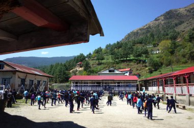Solukhumbu, Everest Bölgesi, Nepal - 2 Mayıs 2019: Junbesi şerpa köyünde okul bahçesinde sabah egzersizi yapan öğrenciler