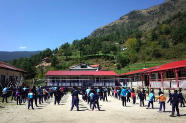 Solukhumbu, Everest Bölgesi, Nepal - 2 Mayıs 2019: Junbesi şerpa köyünde okul bahçesinde sabah egzersizi yapan öğrenciler