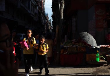 Kathmandu, Nepal - 20 Haziran 2019: Güneş iki okul çocuğu üzerine parlıyor, kardeş ve kardeş eski kasabadaki dar yolda yürüyor, yerel günlük yaşam
