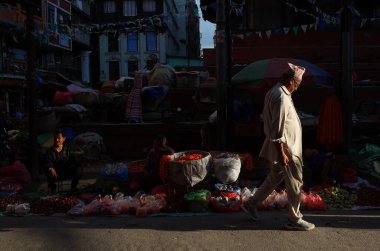 Katmandu, Nepal - 20 Haziran 2019: Geleneksel giysiler içinde güneş Nepalli adamın üzerinde parlıyor Eski kasabadaki dar alışveriş caddesinde yürüyor, yerel günlük yaşam