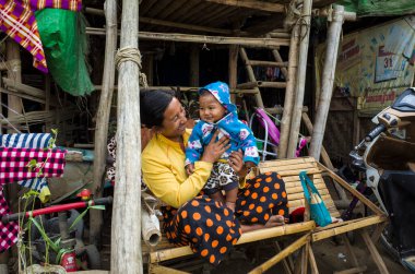 Mandalay, Myanmar - 3 Ocak 2019: Mutlu Burmalı insanlar, kadın ve erkek çocuklar birbirlerine gülümsüyor, gecekondu mahallesinde bambu bankta oturuyorlar.