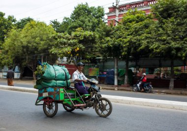 Mandalay, Myanmar - 3 Ocak 2020: Sokakta mavi arka planlı motosiklet kullanan adam