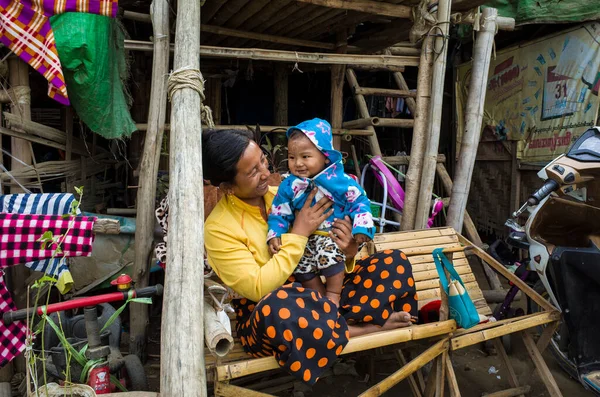 Mandalay, Myanmar - 3 Ocak 2019: Mutlu Burmalı insanlar, kadın ve erkek çocuklar birbirlerine gülümsüyor, gecekondu mahallesinde bambu bankta oturuyorlar.