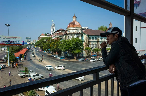 ヤンゴン ミャンマー 2019年12月29日 ヤンゴンのダウンタウンにあるストランド道路とパンソダン通りの交差点にあるヤンゴン地方裁判所の古い植民地時代の建物を眺めながら Pansodan Passの若い男 — ストック写真