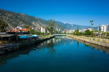 Finike, Türkiye - 26 Ekim 2019: Akcay nehri yanında yerleşim alanı ve restoranı, arka planda dağlar, mavi gökyüzü, Antalya ili