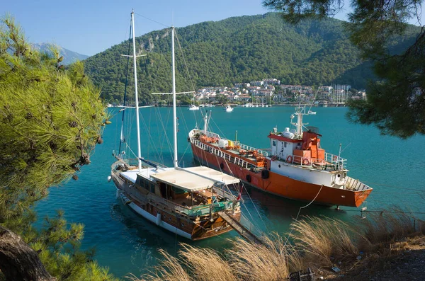 トルコ フェティエ 2019年9月28日 美しい緑の山々に囲まれたターコイズブルーの水で小さな湾にドッキングされた大きな木製のヨットとオレンジ色の鉄の船 — ストック写真