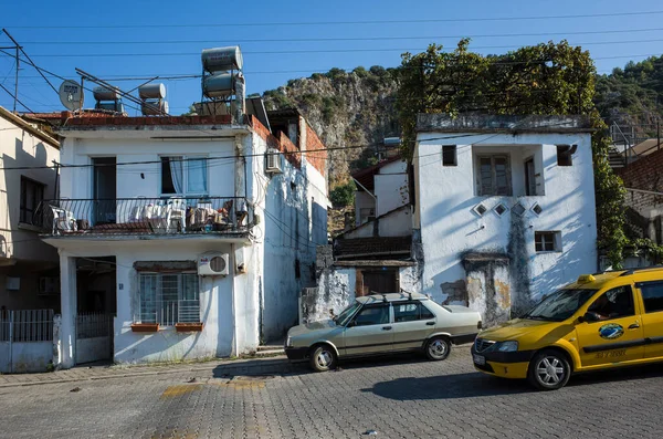 Fethiye, Türkiye - 29 Eylül 2019: Tepedeki ev cephesindeki tipik Akdeniz mahallesi trafik, sarı taksi ve eski araba, günlük sokak fotoğrafı