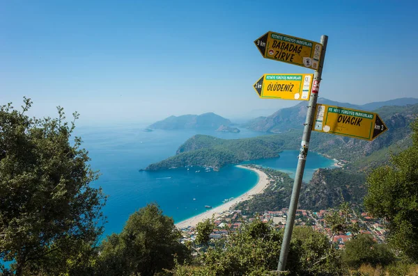 Oludeniz, Türkiye - 1 Ekim 2019: Oludeniz sahili ve Akdeniz kıyısındaki Mavi Göl manzaralı Lycian Yolu sarı tabela direği