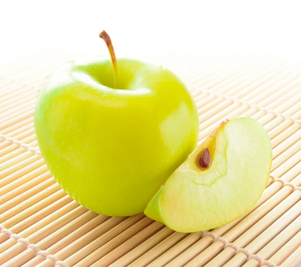 Manzana amarilla con rodaja de manzana en la estera de bambú — Foto de Stock