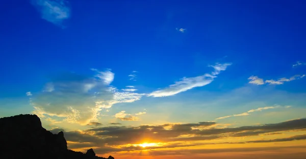 Pôr do sol bonito com céu laranja nublado e silhueta de montanha — Fotografia de Stock