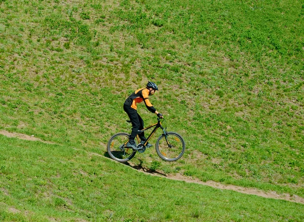Велогонщик едет вниз по холму на заднем колесе — стоковое фото