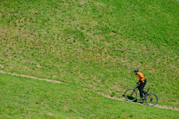 Fietser rijden de groene heuvel — Stockfoto